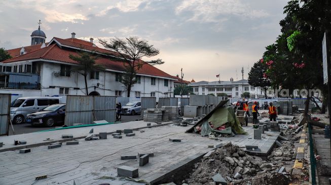 Pekerja menyelesaikan proyek revitalisasi jalur pedestrian di kawasan Kota Tua, Jakarta Barat, Kamis (19/5/2022). [Suara.com/Alfian Winanto]