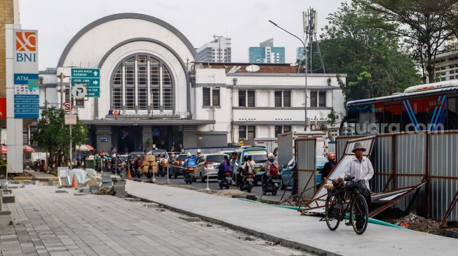 Warga berjalan di jalur pedestrian yang masih dalam tahap revitalisasi di kawasan Kota Tua, Jakarta Barat, Kamis (19/5/2022). [Suara.com/Alfian Winanto]