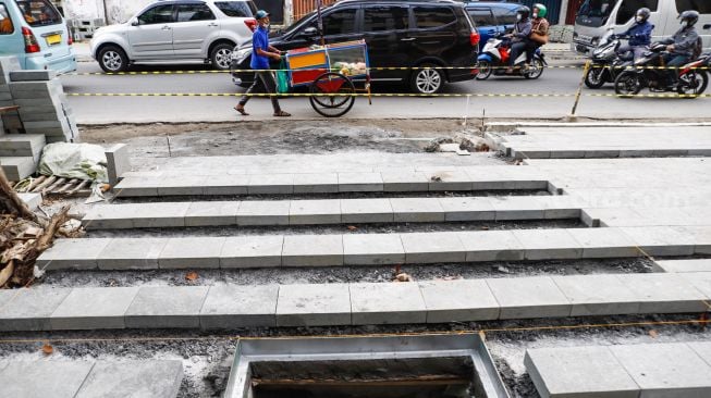 Pekerja menyelesaikan proyek revitalisasi jalur pedestrian di kawasan Kota Tua, Jakarta Barat, Kamis (19/5/2022). [Suara.com/Alfian Winanto]