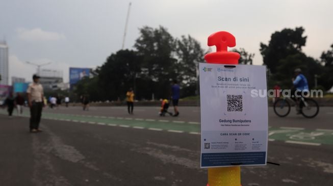 Kode batang untuk memindai aplikasi PeduliLindungi dipasang area 'car free day' (CFD) di Jalan Jenderal Sudirman, Jakarta, Minggu (22/5/2022). [Suara.com/Angga Budhiyanto]