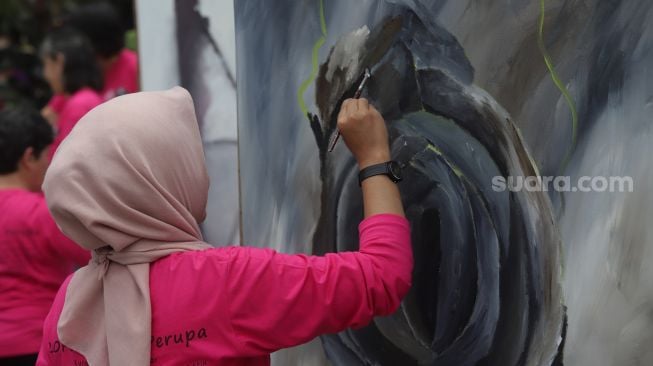 Seniman yang tergabung dalam Perempuan Perupa Indonesia melukis dan menggelar pameran bersama di depan Pos Polisi Thamrin, Jakarta, Minggu (22/5/2022). [Suara.com/Angga Budhiyanto]