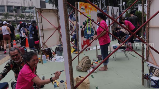 Seniman yang tergabung dalam Perempuan Perupa Indonesia melukis dan menggelar pameran bersama di depan Pos Polisi Thamrin, Jakarta, Minggu (22/5/2022). [Suara.com/Angga Budhiyanto]