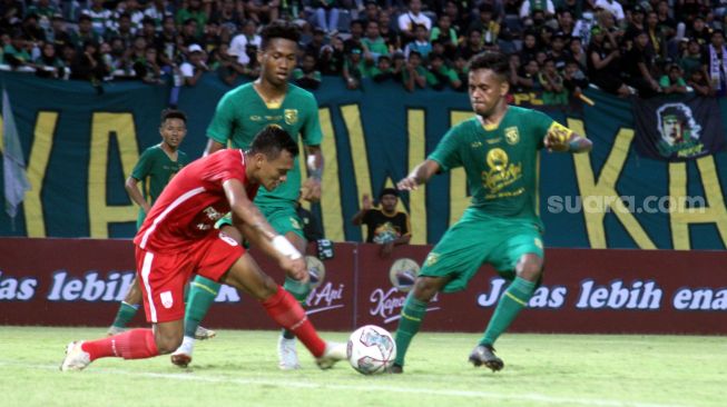 Striker Persis Solo, Ferdinand Sinaga berusaha melewati dua pemain Persebaya Surabaya di Stadion Gelora Bung Tomo, Minggu (22/5/2022). [Suara.com/Ronald Seger Prabowo]