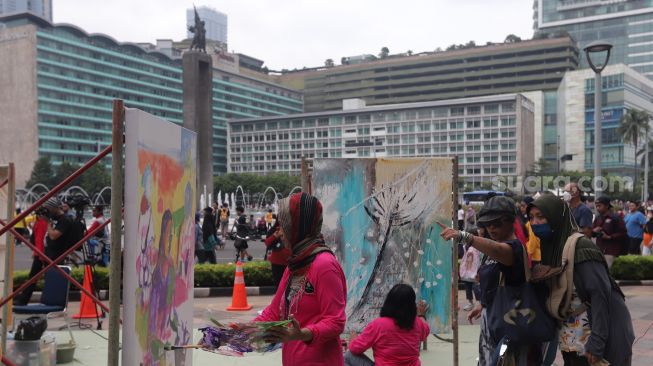 Seniman yang tergabung dalam Perempuan Perupa Indonesia melukis dan menggelar pameran bersama di depan Pos Polisi Thamrin, Jakarta, Minggu (22/5/2022). [Suara.com/Angga Budhiyanto]