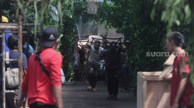 Pekerja membawa bangku saat membongkar dekorasi pernikahan di kediaman Maudy Ayunda di kawasan Cilandak, Jakarta, Senin (23/5/2022). [Suara.com/Angga Budhiyanto]