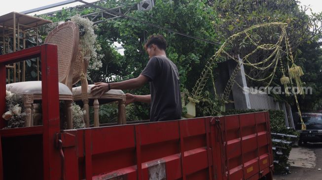 Pekerja menaikkan bangku ke atas truk saat membongkar dekorasi pernikahan di kediaman Maudy Ayunda di kawasan Cilandak, Jakarta, Senin (23/5/2022). [Suara.com/Angga Budhiyanto]