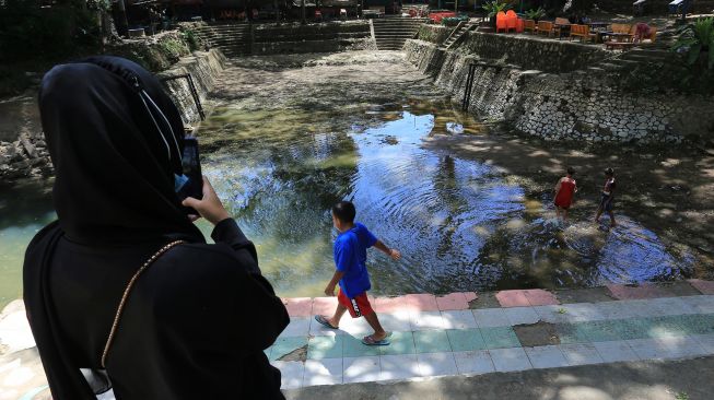 Sejumlah anak bermain di objek wisata pemandian Mata Ie yang kering di Desa Geundring, Darul Imarah, Aceh Besar, Aceh, Selasa (24/5/2022).  ANTARA FOTO/Syifa Yulinnas