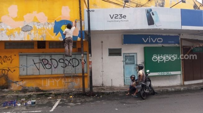 Seniman mural Subki a.k.a SmArt mulai melukis mural di tembok Toko Buku Jaya di Jalan Pajajaran, Kota Magelang [Suara.com/ Angga Haksoro Ardi]