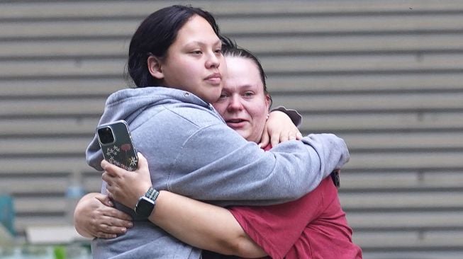 Anggota keluarga berkumpul di luar Ssgt Willie de Leon Civic Center, tempat para siswa dipindahkan dari Sekolah Dasar Robb setelah penembakan, di Uvalde, Texas, AS (24/5/2022).  allison / AFP