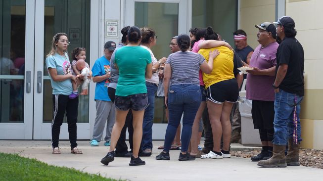 Anggota keluarga berkumpul di luar Ssgt Willie de Leon Civic Center, tempat para siswa dipindahkan dari Sekolah Dasar Robb setelah penembakan, di Uvalde, Texas, AS (24/5/2022).  allison / AFP