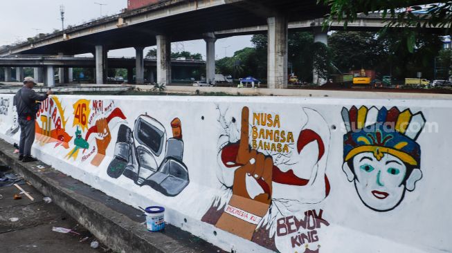 Petugas PPSU membuat mural pada tembok di Jalan R.E Martadinata, Tanjung Priok, Jakarta Utara, Rabu (25/5/2022). [Suara.com/Alfian Winanto]