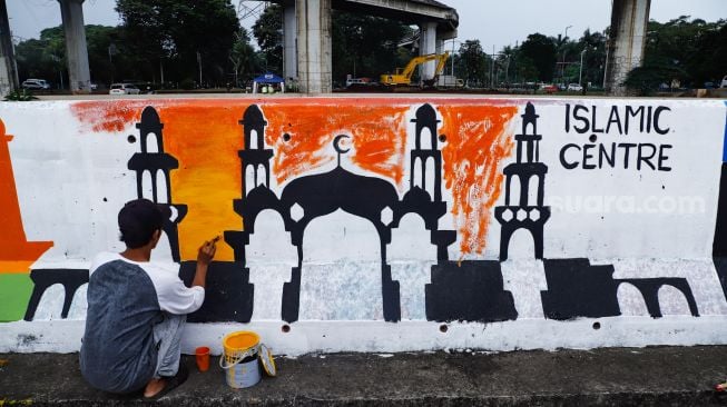 Petugas PPSU membuat mural pada tembok di Jalan R.E Martadinata, Tanjung Priok, Jakarta Utara, Rabu (25/5/2022). [Suara.com/Alfian Winanto]