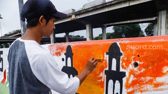 Petugas PPSU membuat mural pada tembok di Jalan R.E Martadinata, Tanjung Priok, Jakarta Utara, Rabu (25/5/2022). [Suara.com/Alfian Winanto]