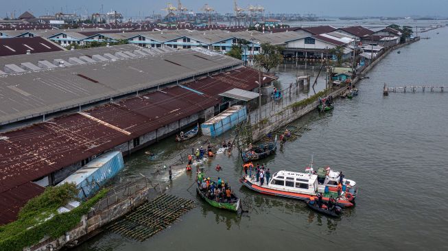 Foto udara personel kepolisian dari Polsek Kesatuan Pelaksanaan Pengamanan Pelabuhan (KP3) Tanjung Emas Semarang bersama warga dan relawan bergotong royong menutup tembok kawasan industri atau tanggul yang jebol dengan konstruksi pagar bambu dan karung berisi pasir dan batu di kawasan industri Pelabuhan Tanjung Emas Semarang, Jawa Tengah, Rabu (25/5/2022).  ANTARA FOTO/Aji Styawan