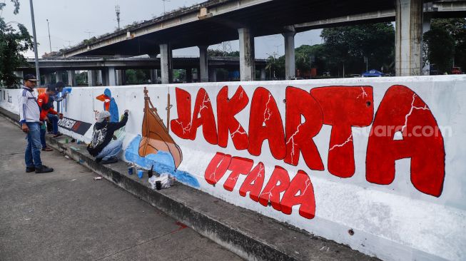 Petugas PPSU membuat mural pada tembok di Jalan R.E Martadinata, Tanjung Priok, Jakarta Utara, Rabu (25/5/2022). [Suara.com/Alfian Winanto]