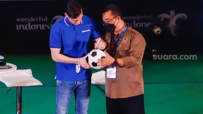 Pesepakbola Mesut Ozil menandatangani bola untuk fans dalam konferensi pers di Kementerian Pariwisata, Ekonomi dan Kreatif (Kemenparekraf), Jakarta Pusat, Rabu (25/5/2022). [Suara.com/Alfian Winanto]