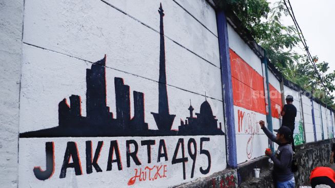 Petugas PPSU membuat mural pada tembok di Jalan R.E Martadinata, Tanjung Priok, Jakarta Utara, Rabu (25/5/2022). [Suara.com/Alfian Winanto]