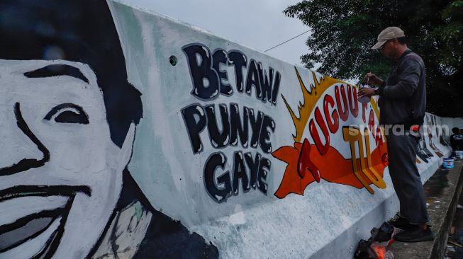 Petugas PPSU membuat mural pada tembok di Jalan R.E Martadinata, Tanjung Priok, Jakarta Utara, Rabu (25/5/2022). [Suara.com/Alfian Winanto]