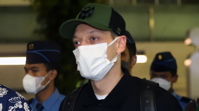 Mantan pesepak bola Timnas Jerman Mesut Ozil (kedua kanan) berjalan keluar setibanya di Bandara Soekarno Hatta, Tangerang, Banten, Selasa (24/5/2020).  ANTARA FOTO/Muhammad Iqbal