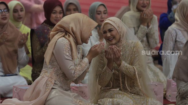 Artis Juliana Moechtar (kanan) memanjatkan doa saat akad nikah di Masjid Istiqlal, Jakarta, Jumat (27/5/2022). [Suara.com/Angga Budhiyanto]