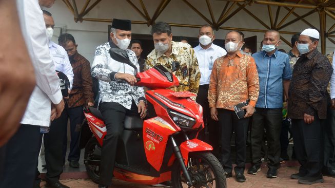 Gubernur Aceh, Nova Iriansyah (keempat kanan) bersiap mengendarai sepeda motor listrik saat penyerahan untuk tugas operasional instansi pemerintah di Banda Aceh,Aceh Jumat (27/5/2022). ANTARA FOTO/Ampelsa