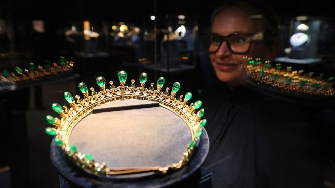 Seorang karyawan Sotheby mempelajari tiara zamrud dan berlian Ratu Victoria saat sesi pemotretan untuk mempromosikan Sotheby's Jubilee Season, di London, Inggris, Jumat (27/5/2022). [ADRIAN DENNIS / AFP]