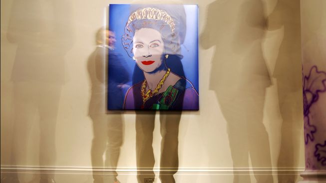 Orang-orang mempelajari "Reigning Queens: Queen Elizabeth II of the United Kingdom" oleh seniman Amerika Andy Warhol saat sesi pemotretan untuk mempromosikan Sotheby's Jubilee Season, di London, Inggris, Jumat (27/5/2022). [ADRIAN DENNIS / AFP]