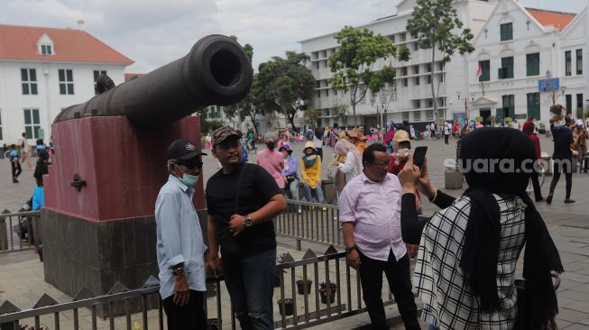 Warga berfoto di Taman Fatahillah, Kota Tua, Jakarta, Minggu (29/5/2022). [Suara.com/Angga Budhiyanto]