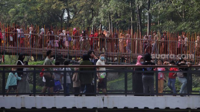 Warga melintasi jembatan Tebet Eco Park di Jakarta, Minggu (29/5/2022). [Suara.com/Angga Budhiyanto]