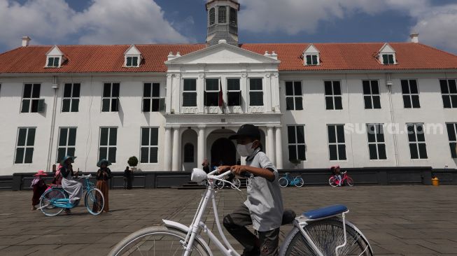 Warga menaiki sepeda saat berwisata di Taman Fatahillah, Kota Tua, Jakarta, Minggu (29/5/2022). [Suara.com/Angga Budhiyanto]