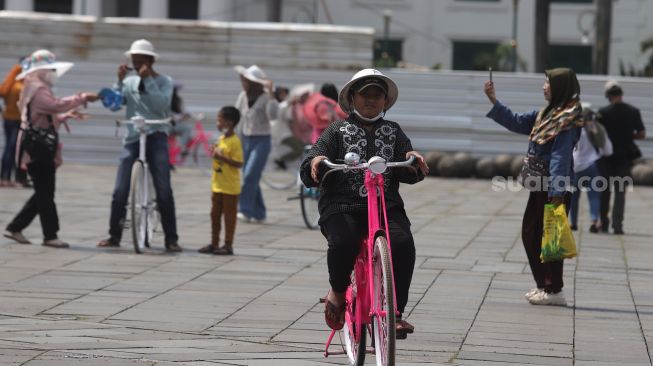 Warga menaiki sepeda saat berwisata di Taman Fatahillah, Kota Tua, Jakarta, Minggu (29/5/2022). [Suara.com/Angga Budhiyanto]