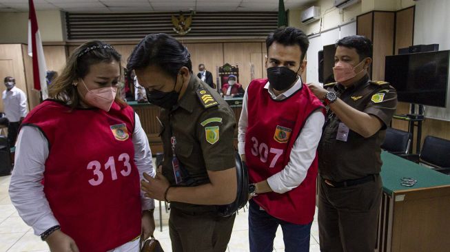 Terdakwa kasus pelanggaran Undang-Undang (UU) ITE Adam DeniGearaka (kedua kanan) dan Ni Made Dwita (kiri) dengan penjagaan petugas kejaksaan bergegas usai menjalani sidang pembacaan tuntutan di Pengadilan Negeri Jakarta Utara, Jakarta, Senin (30/5/2022). ANTARA FOTO/Dhemas Reviyanto