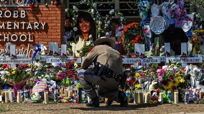 Bunga, mainan, dan sejumlah benda lain diletakkan di tugu peringatan untuk para korban penembakan sekolah yang mengakibatkan kematian 19 anak dan dua guru di Robb Elementary School, Uvalde, Texas, Amerika Serikat, Minggu (29/5/2022). . [AFP/Photo]
