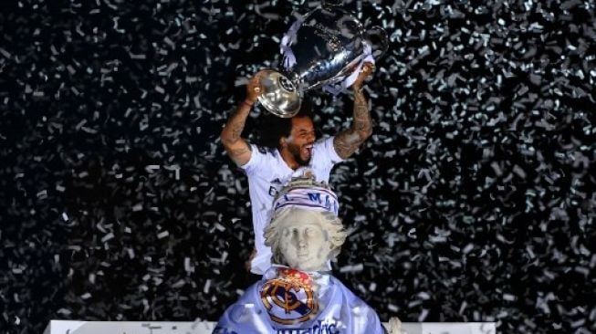 Bek Real Madrid Brasil Marcelo mengangkat trofi mereka di atas patung dewi Yunani Cybele pada 29 Mei 2022 di alun-alun Cibeles di Madrid, sehari setelah mengalahkan Liverpool di final Liga Champions UEFA di Paris.GABRIEL BOUYS / AFP