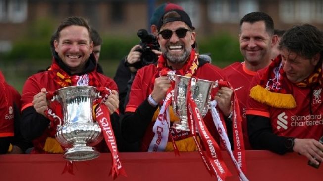 Asisten manajer Liverpool Pepikn Lijnders memegang Piala FA dan manajer Jerman Liverpool Jurgen Klopp memegang Piala Liga saat mereka merayakan dari bus terbuka selama parade melalui jalan-jalan Liverpool, Inggris pada 29 Mei 2022. Oli Scarf / AFP