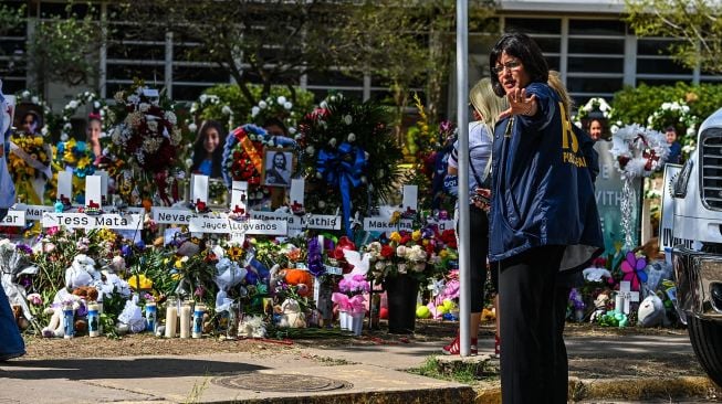 Bunga, mainan, dan sejumlah benda lain diletakkan di tugu peringatan untuk para korban penembakan sekolah yang mengakibatkan kematian 19 anak dan dua guru di Robb Elementary School, Uvalde, Texas, Amerika Serikat, Minggu (29/5/2022). . [AFP/Photo]
