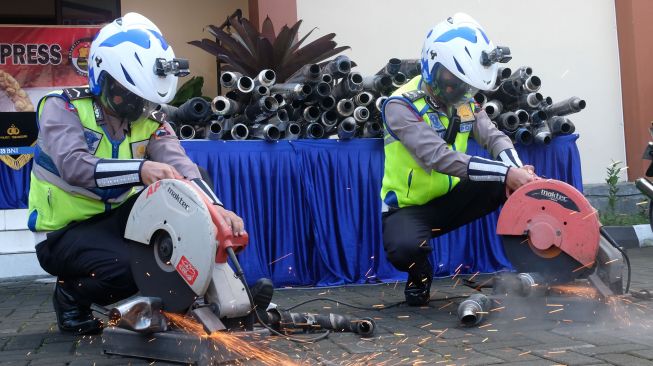 Personel polisi memotong knalpot brong atau knalpot tidak standar saat gelar perkara penindakan kasus knalpot brong di Mapolres Temanggung, Jawa Tengah, Kamis (2/6/2022).  ANTARA FOTO/Anis Efizudin