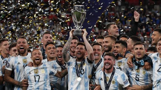 Kapten timnas Argentina Lionel Messi (tengah) mengangkat piala Conembol-UEFA Cup of Champions setelah mengalahkan Italia dengan skor 3-0 padaFinallisima di Stadion Wembley, London, Kamis (2/6/2022) dini hari WIB. [AFP]
