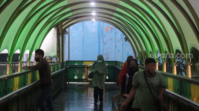 Warga berjalan di jembatan penyeberangan orang (JPO) di kawasan Pasar Minggu, Jakarta, Kamis (2/6/2022). [Suara.com/Angga Budhiyanto]