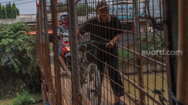 Pengendara motor melintasi Jembatan Penyebrangan Orang (JPO) di atas sungai Kalimalang di Jl. KH. Noer Ali, Kalimalang, Jakarta Timur, Kamis (2/6/2022). [Suara.com/Alfian Winanto]