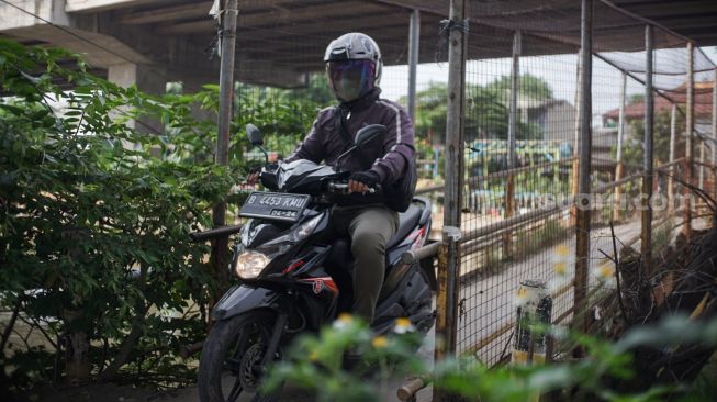 Pengendara motor melintasi Jembatan Penyebrangan Orang (JPO) di atas sungai Kalimalang di Jl. KH. Noer Ali, Kalimalang, Jakarta Timur, Kamis (2/6/2022). [Suara.com/Alfian Winanto]