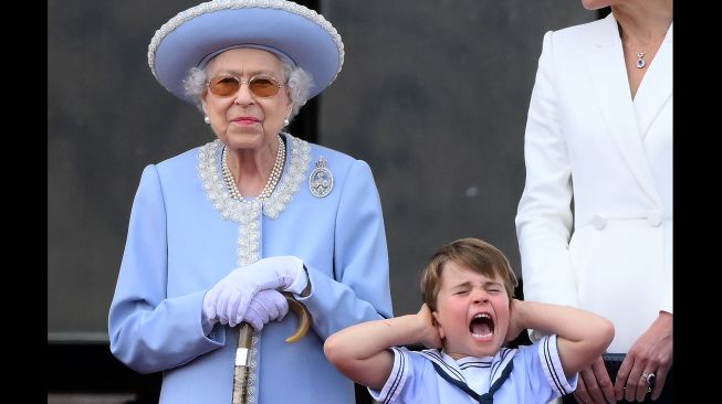 Pangeran Louis memegang telinganya di samping Ratu Inggris Elizabeth II ketika menyaksikan atraksi pesawat khusus dari balkon Istana Buckingham saat perayaan 70 tahun tahta Ratu atau Queen Platinum Jubilee di London, Ingrris, Kamis (2/6/2022). [Daniel LEAL / AFP]
