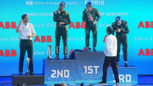 Pembalap Jaguar TCS Mitch Evans (tengah) mencium trofi yang diberikan Presiden Joko Widodo (kedua kanan) usai menjuarai balapan Formula E seri kesembilan di Jakarta International E-Prix Circuit (JIEC), Jakarta, Sabtu (4/6/2022). [ANTARA FOTO/Indrianto Eko Suwarso/aww]
