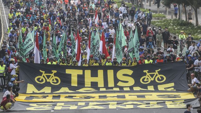 Sejumlah aktivis Greenpeace dan Bike2Work membentangkan spanduk saat aksi memperingati Hari Lingkungan Hidup Sedunia di Jalan Sudirman, Jakarta, Minggu (5/6/2022).  ANTARA FOTO/Asprilla Dwi Adha