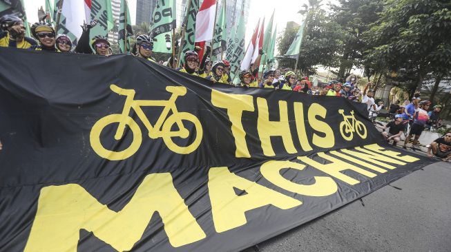 Sejumlah aktivis Greenpeace dan Bike2Work membentangkan spanduk saat aksi memperingati Hari Lingkungan Hidup Sedunia di Jalan Sudirman, Jakarta, Minggu (5/6/2022).  ANTARA FOTO/Asprilla Dwi Adha