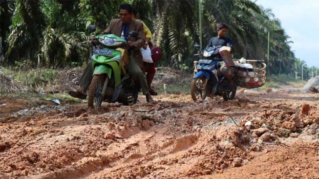 Warga Bengkalis melintasi jalanan rusak dan berlumpur untuk bisa sampai ke sekolah. [Suara.com/Panji Ahmad Syuhada]