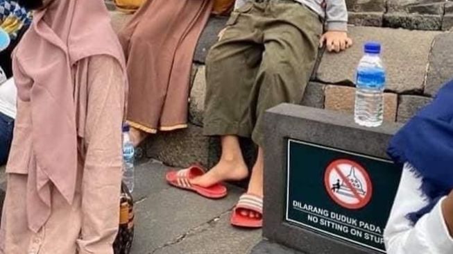 Wisatawan duduk dan panjat stupa Candi Borobudur walau sudah dilarang. (Twitter/@OrangNgetweet)