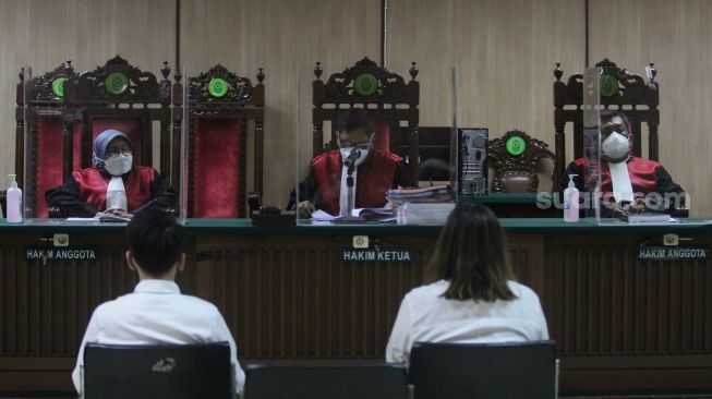 Terdakwa kasus pelanggaran Undang-Undang (UU) ITE Adam Deni (kiri) dan  Ni Made Dwita mengikuti sidang lanjutan dengan agenda pembacaan nota pembelaan atau pledoi di Pengadilan Negeri Jakarta Pusat, Selasa (7/6/2022). [Suara.com/Angga Budhiyanto]