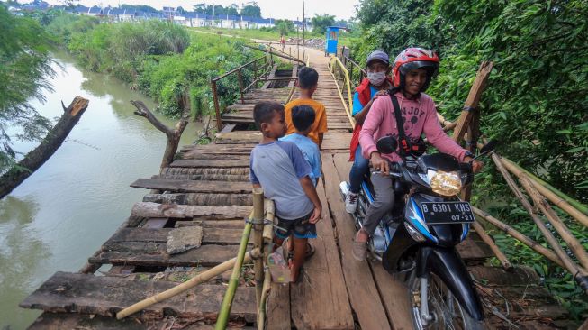 Warga melintasi akses jembatan yang rusak penghubung antara kecamatan Jonggol dan kecamatan Klapanunggal di Singasari, Jonggol, Kabupaten Bogor, Jawa Barat, Selasa (7/6/2022). [ANTARA FOTO/Yulius Satria Wijaya/foc]