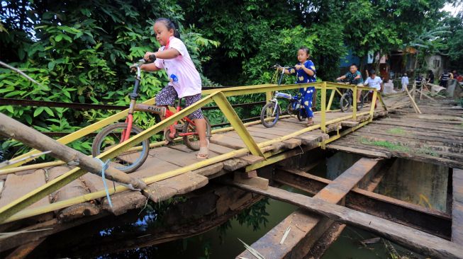 Sejumlah anak melintasi akses jembatan yang rusak penghubung antara kecamatan Jonggol dan kecamatan Klapanunggal di Singasari, Jonggol, Kabupaten Bogor, Jawa Barat, Selasa (7/6/2022). [ANTARA FOTO/Yulius Satria Wijaya/foc]